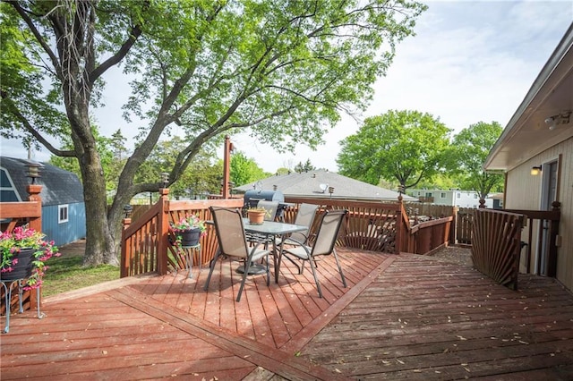 wooden deck featuring outdoor dining area, a shed, and an outbuilding
