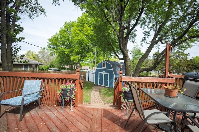wooden deck featuring fence, a storage unit, an outbuilding, and outdoor dining area