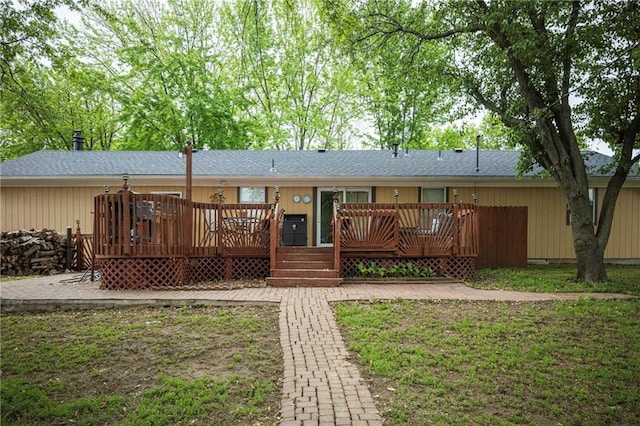 rear view of property with roof with shingles and a deck