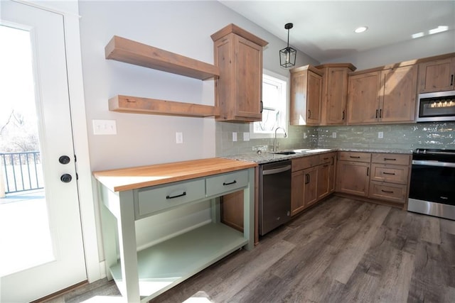 kitchen with open shelves, decorative backsplash, dark wood finished floors, hanging light fixtures, and stainless steel appliances