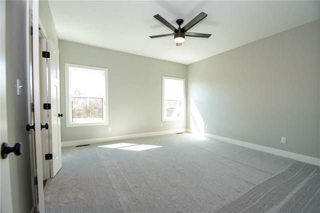 carpeted spare room with baseboards, plenty of natural light, and a ceiling fan