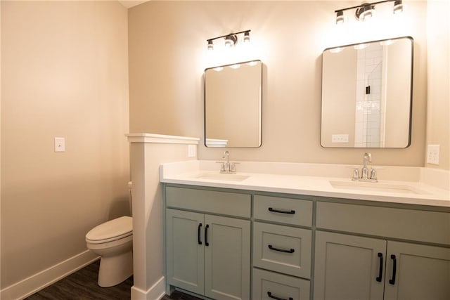 full bathroom featuring double vanity, wood finished floors, a sink, baseboards, and toilet