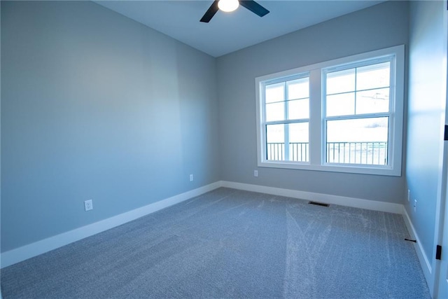 spare room featuring a ceiling fan, baseboards, visible vents, and dark carpet