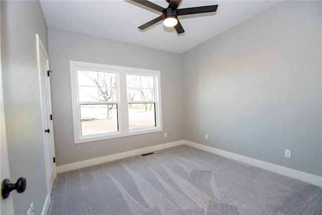 carpeted empty room with baseboards, a ceiling fan, and visible vents