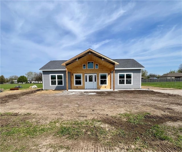 back of property with fence and a shingled roof