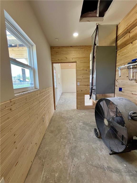 corridor featuring wooden walls and unfinished concrete flooring
