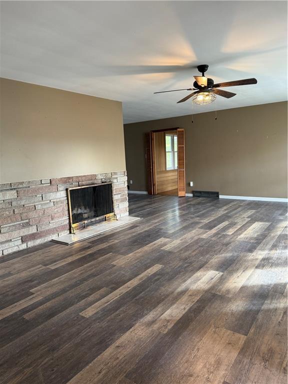 1020 Francis St, Lexington, MO 64067 - unfurnished living room with wood finished floors, a fireplace with raised hearth, a ceiling fan, and baseboards