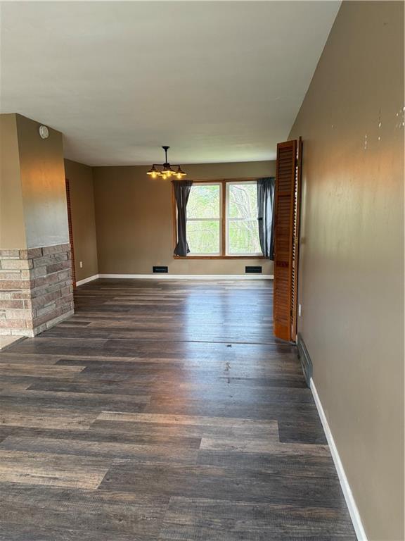 1020 Francis St, Lexington, MO 64067 - empty room with a notable chandelier, baseboards, and dark wood-type flooring