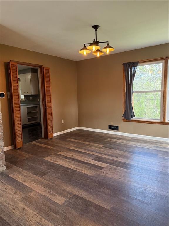 1020 Francis St, Lexington, MO 64067 - empty room featuring baseboards, wood finished floors, and a notable chandelier