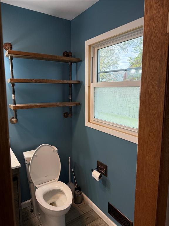 1020 Francis St, Lexington, MO 64067 - half bathroom featuring toilet, baseboards, visible vents, wood finished floors, and vanity