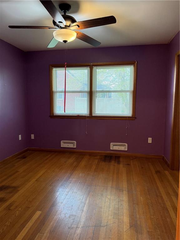1020 Francis St, Lexington, MO 64067 - empty room with baseboards, wood finished floors, ceiling fan, and a healthy amount of sunlight