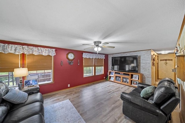 living area featuring baseboards, a textured ceiling, wood finished floors, and a ceiling fan