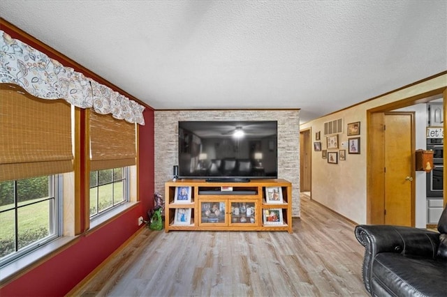 living room featuring visible vents, wood finished floors, ornamental molding, and a textured ceiling