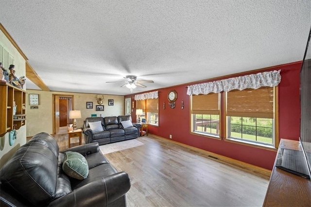 living area with baseboards, a textured ceiling, wood finished floors, and a ceiling fan