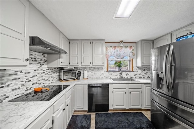 kitchen with wall chimney range hood, light countertops, a sink, and black appliances
