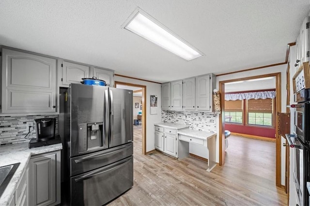 kitchen featuring gray cabinetry, light wood-type flooring, backsplash, and stainless steel appliances
