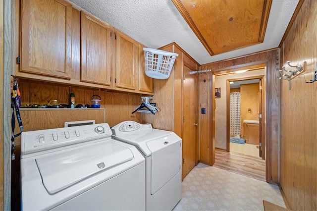 laundry area with independent washer and dryer, wooden walls, cabinet space, and light floors
