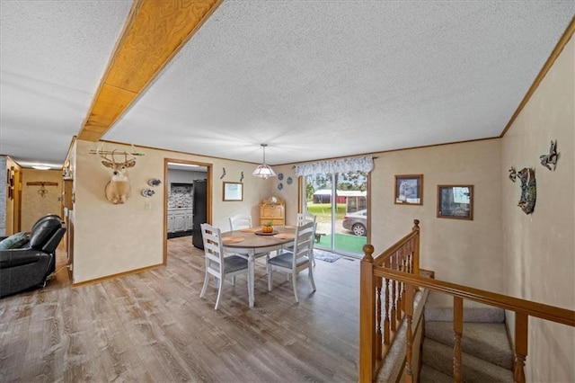 dining room featuring crown molding, a textured ceiling, baseboards, and wood finished floors