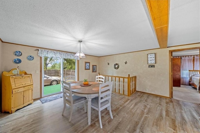 dining space featuring baseboards, light wood-type flooring, and a textured ceiling