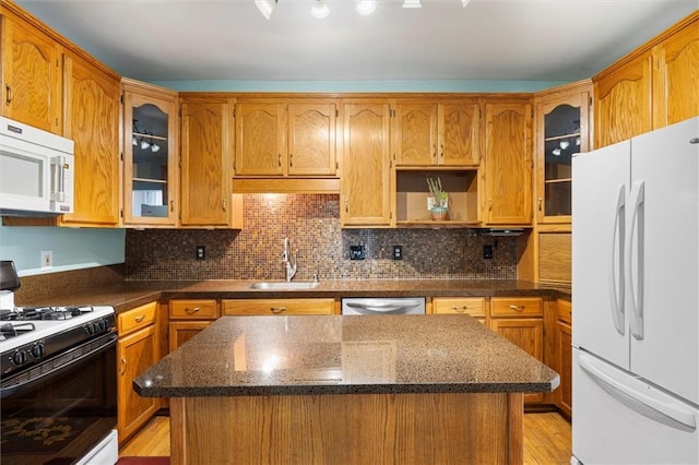kitchen with decorative backsplash, a sink, white appliances, and a kitchen island