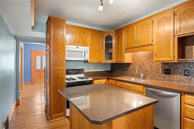 kitchen featuring tasteful backsplash, gas range, a sink, white microwave, and stainless steel dishwasher