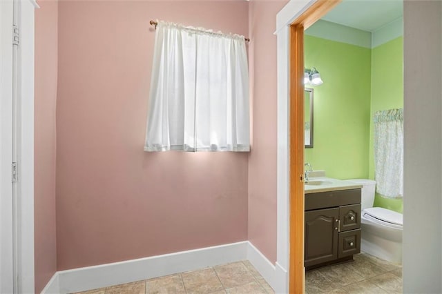 bathroom featuring toilet, vanity, and baseboards