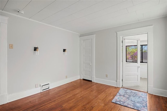 spare room featuring hardwood / wood-style floors, crown molding, and baseboards