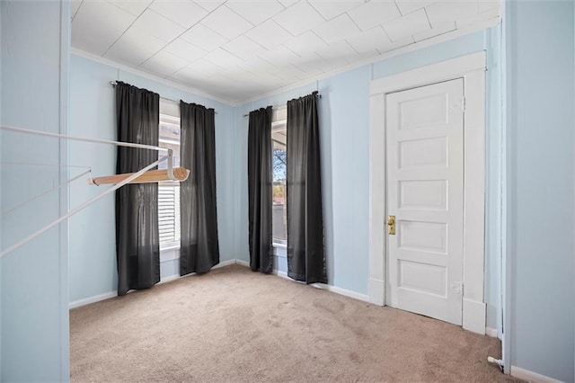 unfurnished bedroom with baseboards, crown molding, and carpet floors