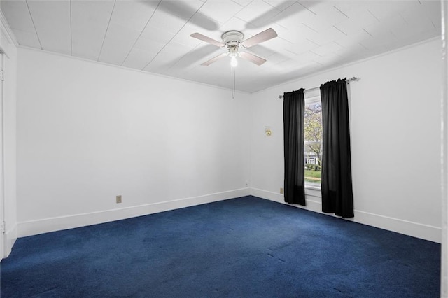 empty room with dark carpet, crown molding, baseboards, and a ceiling fan