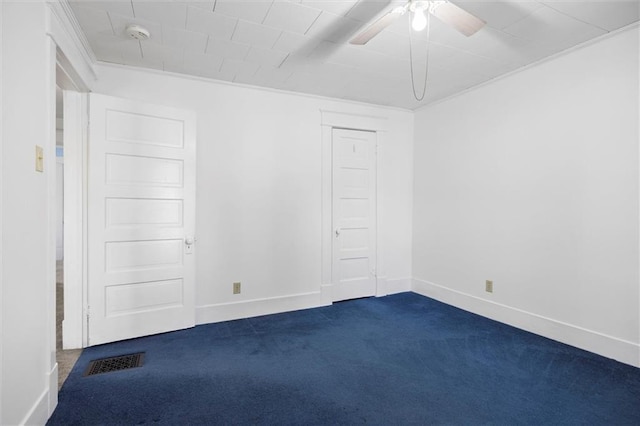 spare room with dark carpet, baseboards, a ceiling fan, and visible vents