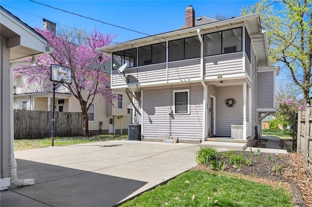 back of house featuring fence, central air condition unit, a sunroom, and a chimney