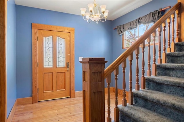 entrance foyer with stairs, baseboards, an inviting chandelier, and wood finished floors