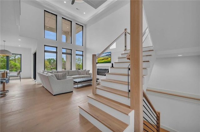 interior space featuring recessed lighting, ceiling fan, stairs, a towering ceiling, and wood finished floors