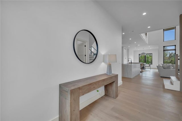 corridor featuring light wood-style floors, recessed lighting, and baseboards