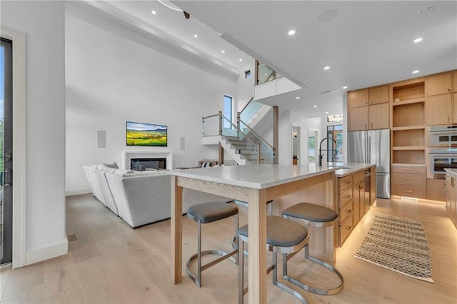 kitchen with a sink, appliances with stainless steel finishes, light brown cabinetry, light wood finished floors, and modern cabinets