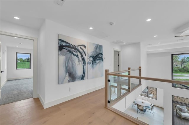 corridor featuring baseboards, recessed lighting, wood finished floors, and an upstairs landing