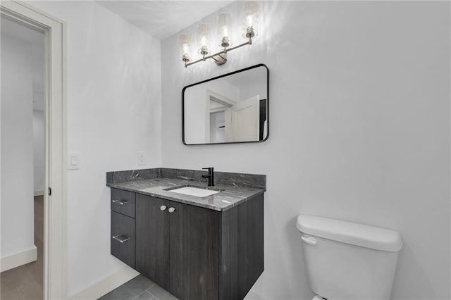 half bathroom with baseboards, toilet, and vanity