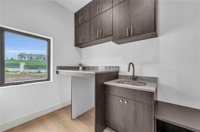 washroom with baseboards, light wood-style floors, and a sink