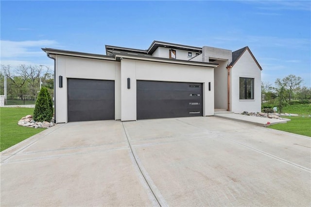 view of front facade with stucco siding, driveway, a front yard, and an attached garage