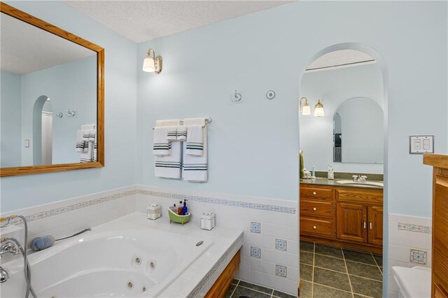 4012 NE Brooktree Ln, Kansas City, MO 64119 - full bathroom featuring vanity, tile patterned flooring, a textured ceiling, a wainscoted wall, and a tub with jets