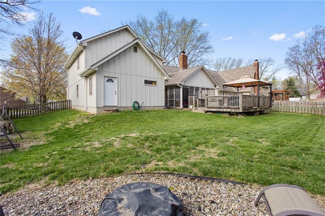 4012 NE Brooktree Ln, Kansas City, MO 64119 - back of house with board and batten siding, a sunroom, a fenced backyard, a lawn, and a deck