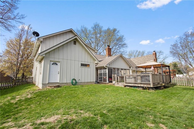 4012 NE Brooktree Ln, Kansas City, MO 64119 - rear view of house with a deck, a sunroom, a lawn, board and batten siding, and a fenced backyard
