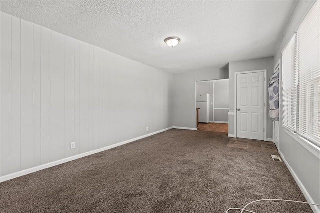 2701 Wilson Ave, Leavenworth, KS 66048 - unfurnished bedroom featuring multiple windows, dark carpet, freestanding refrigerator, and a textured ceiling