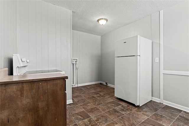 2701 Wilson Ave, Leavenworth, KS 66048 - kitchen with freestanding refrigerator, a textured ceiling, dark stone finish floors, range, and baseboards