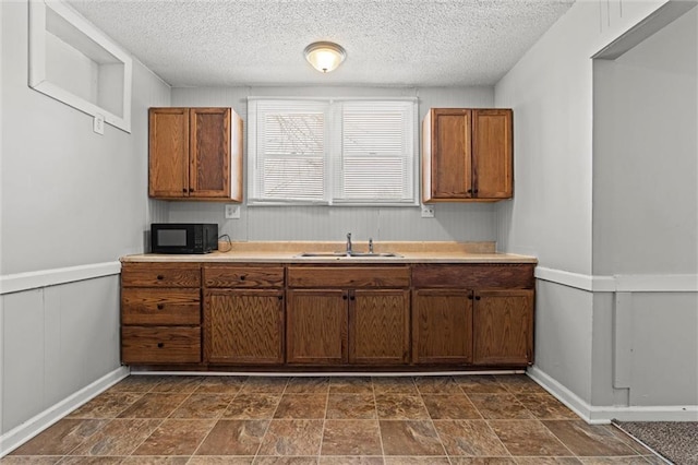 2701 Wilson Ave, Leavenworth, KS 66048 - kitchen with black microwave, brown cabinets, a sink, light countertops, and a textured ceiling