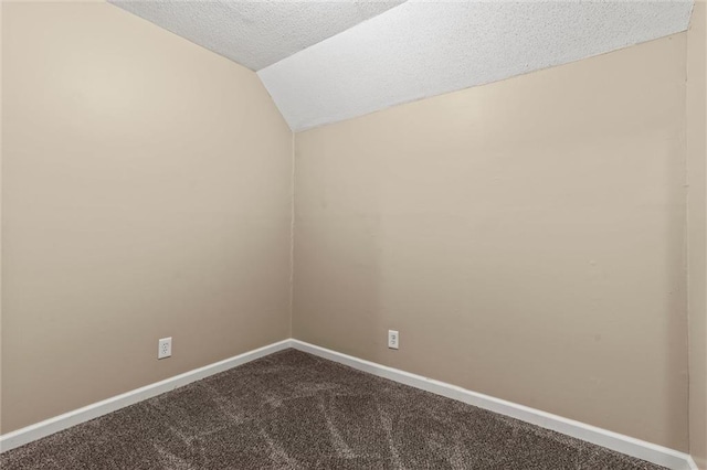 2701 Wilson Ave, Leavenworth, KS 66048 - empty room featuring a textured ceiling, dark colored carpet, vaulted ceiling, and baseboards