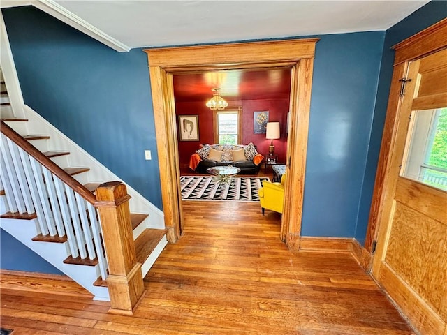 3640 Forest Ave, Kansas City, MO 64109 - hallway featuring wood-type flooring, stairs, baseboards, a chandelier, and ornamental molding