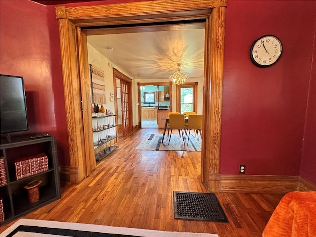 3640 Forest Ave, Kansas City, MO 64109 - hall with wood finished floors, a chandelier, and baseboards