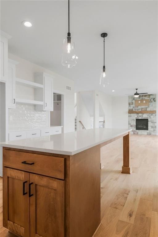 16470 W 166th Pl, Olathe, KS 66062 - kitchen featuring light wood-style floors, open shelves, white cabinets, light countertops, and a stone fireplace