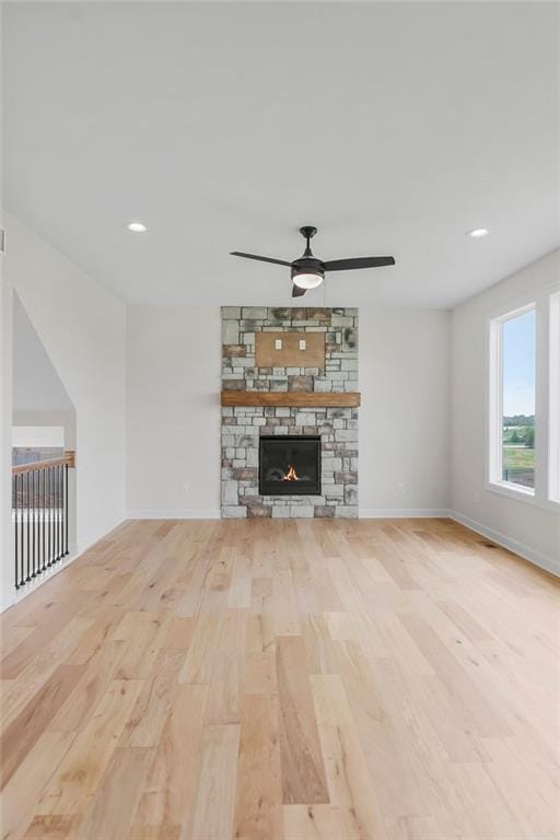 16470 W 166th Pl, Olathe, KS 66062 - unfurnished living room featuring light wood-style floors, a ceiling fan, baseboards, a stone fireplace, and recessed lighting